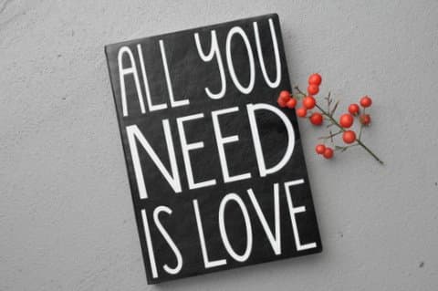 Hand-lettered sign reading "All You Need Is Love"